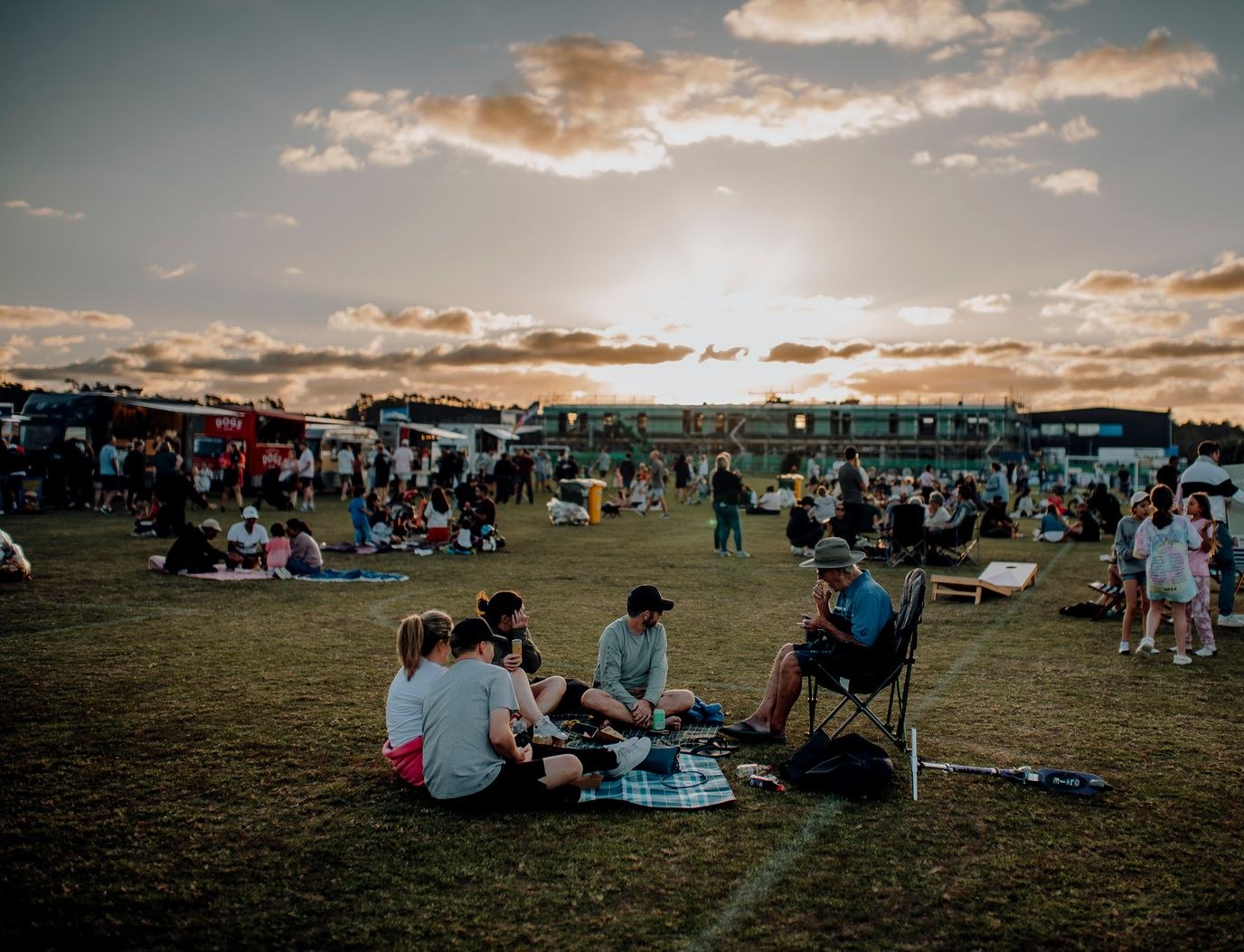 Festival field at golden hour with catering trucks lined up on the horizon